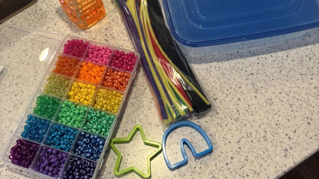 colorful beads, cookie-cutters and pipe-cleaners sit on a table