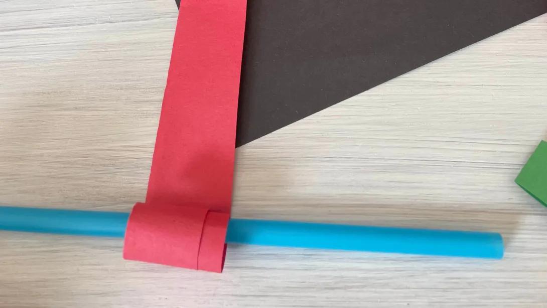 red construction paper strip rolled over a straw