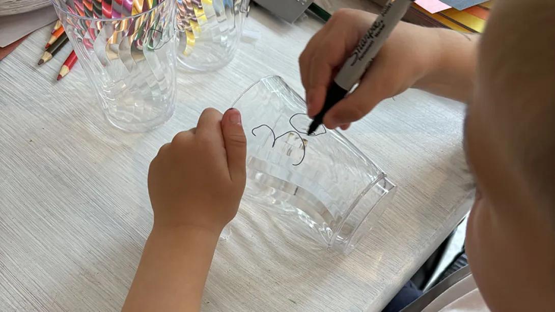 Child drawing number on plastic cup