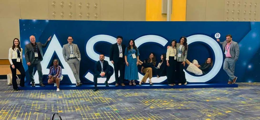 Rogel researchers attending ASCO stand in front of the ASCO sign inside McCormick Place