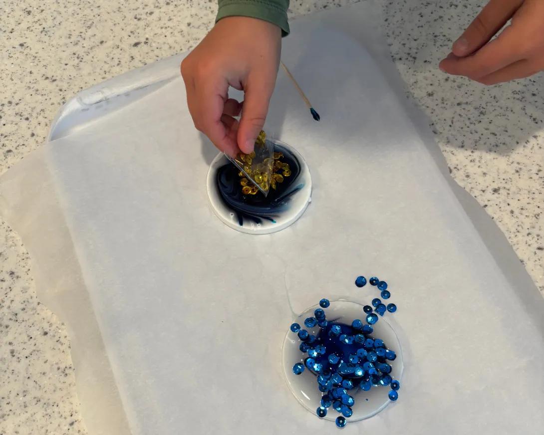 child placing sequins in glue circle